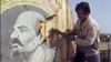 AZERBAIJAN -- A Baku resident cuts out with an axe  21 September 1991 in Baku a placard showing a portrait of Russain Bolshevik revolutionary leader Vladimir Ilyich Lenin.